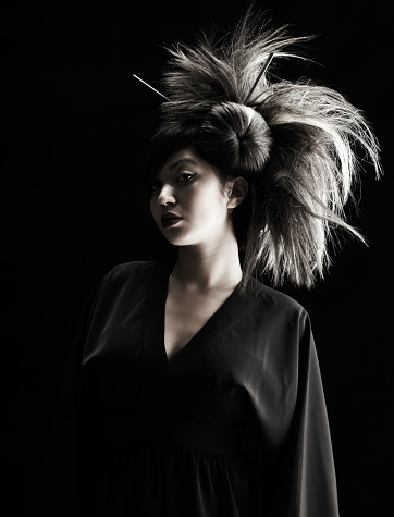 Beautiful Asian Geisha with dramatic hairpiece on gray background.  Vertical shot.