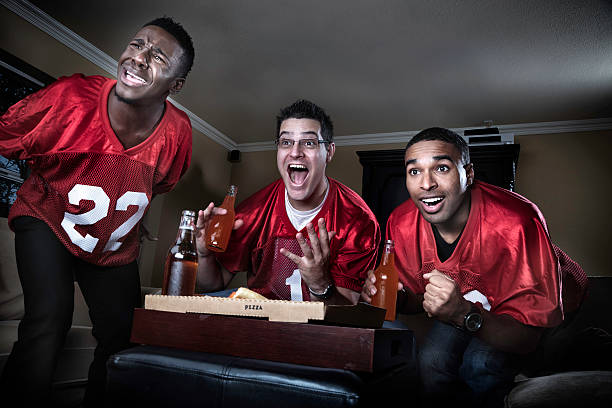freunde beobachten fußballspiel auf fernseher - sitting 20s adult american football stock-fotos und bilder