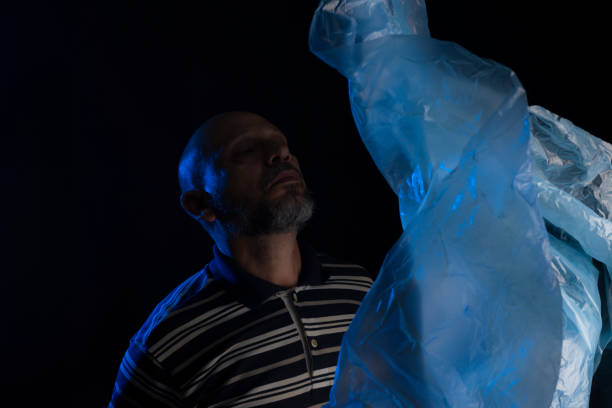 Mature man with a transparent plastic blue bag flying over his head and face. suffocate. face in a plastic bag, strangulation