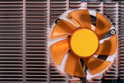 Macro photo of computer graphic card processor cooling system. the fan is in gold color. Shot in studio. No people are seen in frame.