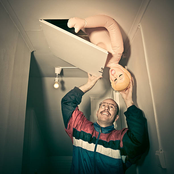 Sexy Time Happy nerdy looking guy takes blow up doll from under roof storage. blow up doll stock pictures, royalty-free photos & images