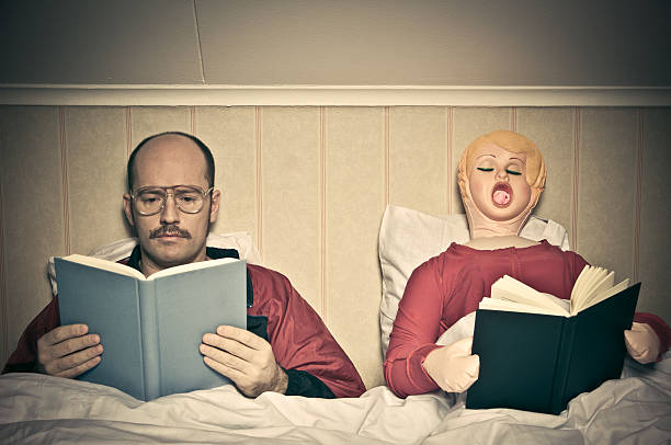 Bed Time Routines Nerdy looking guy and blow up doll reading in bedroom blow up doll stock pictures, royalty-free photos & images