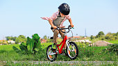 istock Young rider kid in helmet and sunglasses riding bicycle 1439193633