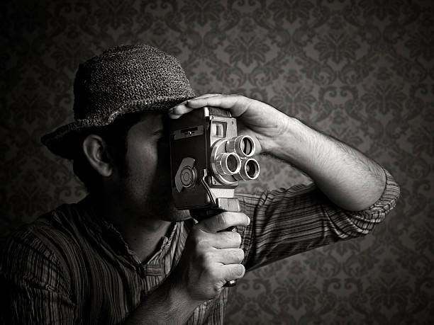 Man using old fashioned cinecamera Man using old fashioned cine camera, black and white image vintage video camera stock pictures, royalty-free photos & images