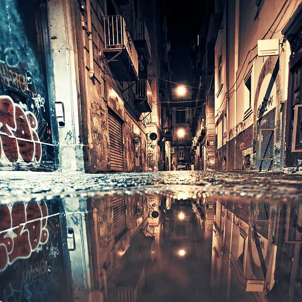 Dark street in old town reflected in puddle.