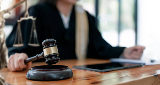 gavel da terra arrendada da mão do juiz da mulher para bater no bloco de sonoridade no quarto da corte. - sala de tribunal - fotografias e filmes do acervo