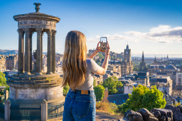 студентка фотографирует со смартфона в эдинбурге на закате с калтон хилл - edinburgh стоковые фото и изображения