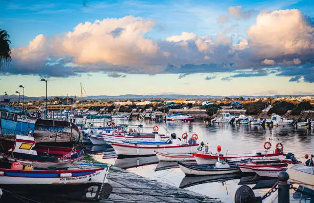 Photo of fishing boats in the fuseta harbor in algarve , portugal at the sunset