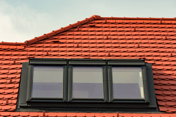 Red new roof tiles with three attic windows with black frame closed.
