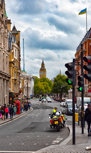 A view from a distance of the Big Ben clock tower in London and in the foreground a busy street and police motorbikes