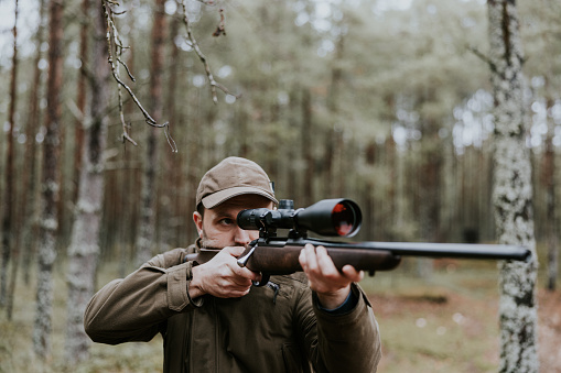 Hunter aiming with hunting rifle in the autumn forest
