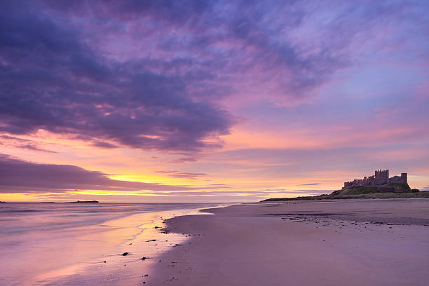 sonnenaufgang am strand in bamburgh castle, northumberland, england - bamburgh stock-fotos und bilder