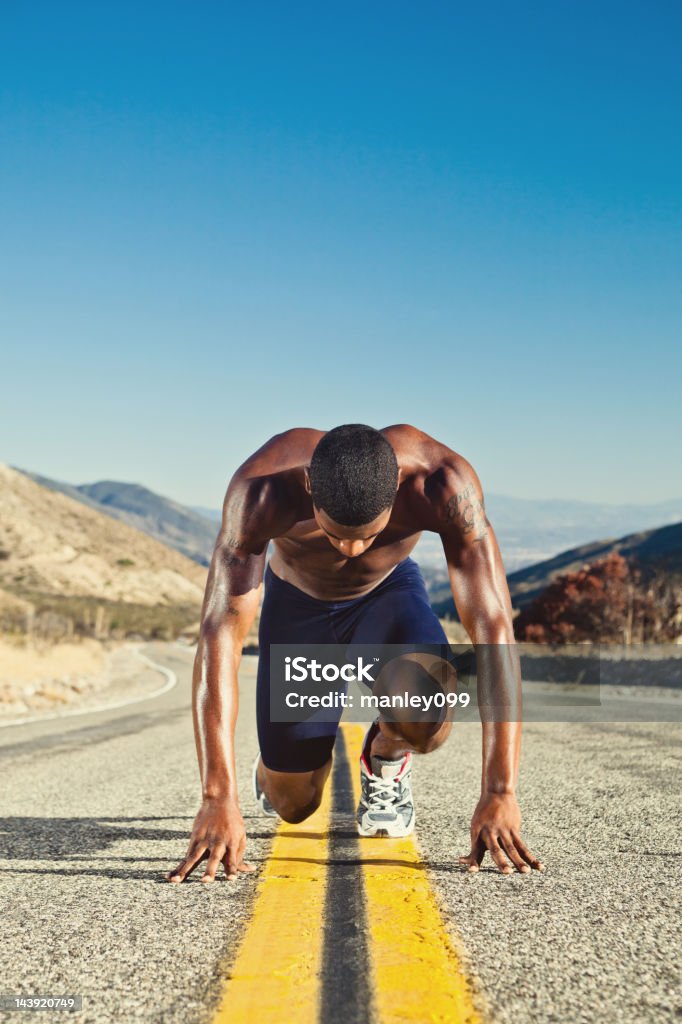 Черный мужской спортсмен выполняет растяжку на Дорога в пустыне - Стоковые фото Активный образ жизни роялти-фри