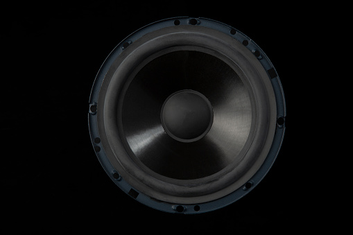 Loudspeakers and subwoofers stacked on each other illuminated by red spotlights on a dark background. Powerful sound system with modern audio equipment for an underground music club where punk and rock music is played. Digitally generated image. Copy space.