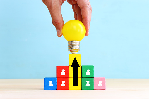 Education and human resource concept image. Creative idea and innovation. light bulb metaphor over blue background, wooden cubes and people icons