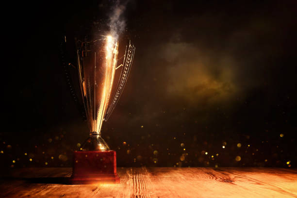 istock image of gold trophy with sparkly overlay over dark background 1439211911