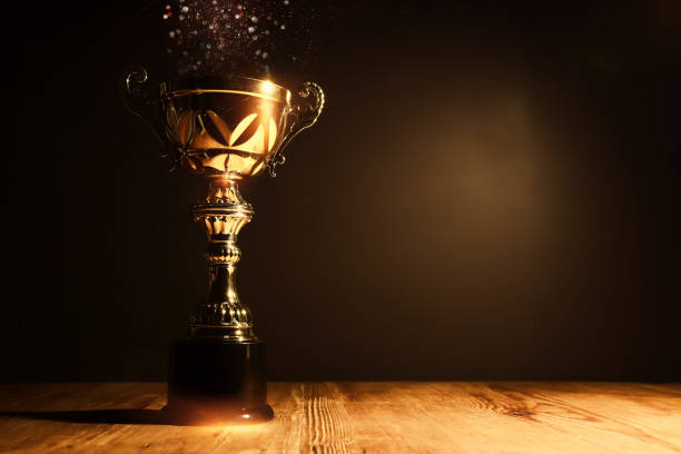 istock image of gold trophy with sparkly overlay over dark background 1439211919