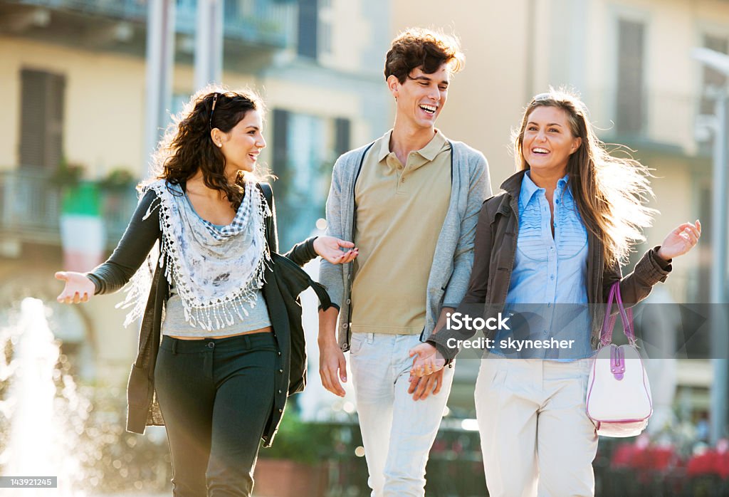 Três amigos caminhando pelas ruas da cidade. - Foto de stock de A caminho royalty-free