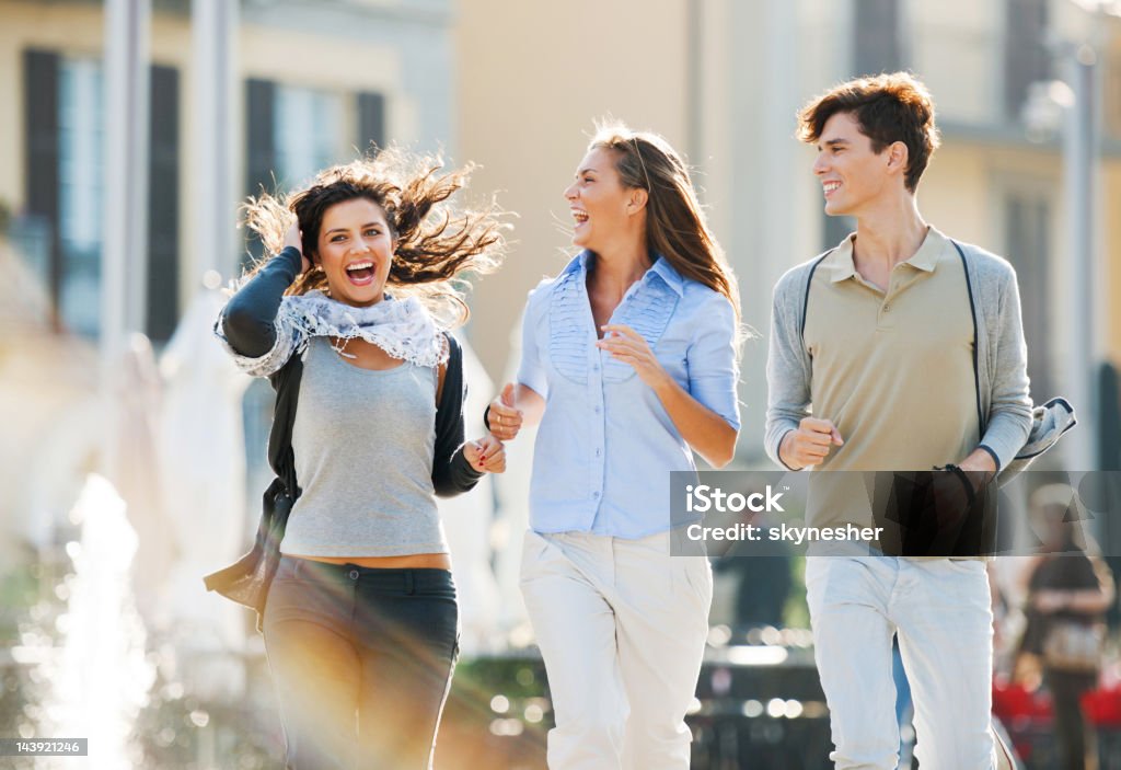 Tres amigos corriendo por las calles de la ciudad. - Foto de stock de Actividad libre de derechos