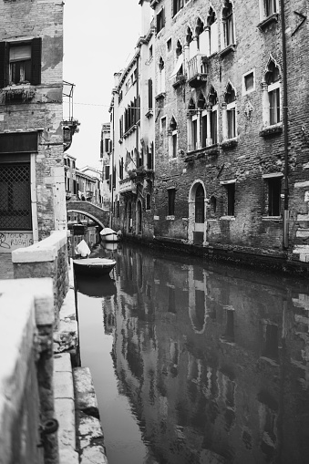 A vertical grayscale picture of a channel in Venice  with beautiful ancient buildings