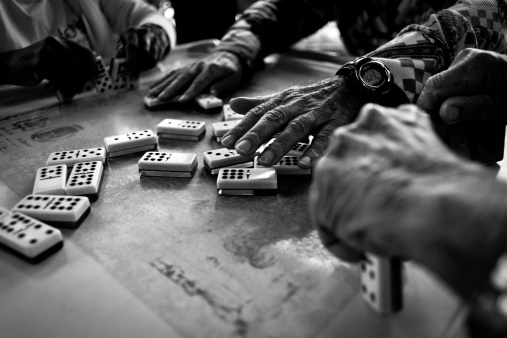 BW close-up image of hands playing dominos.