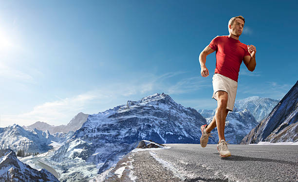 Male athlete in blue goes running in the Alps, the Matterhorn is in full view.