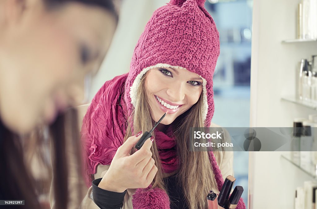 Ragazza dello shopping nel negozio di bellezza prodotti cosmetici e cerca il lucidalabbra - Foto stock royalty-free di Comprare