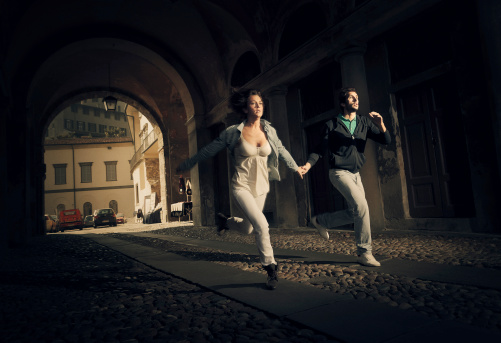 couple running thru an ominous street tunnel in small town of northern italy as someone bad was chasing them.