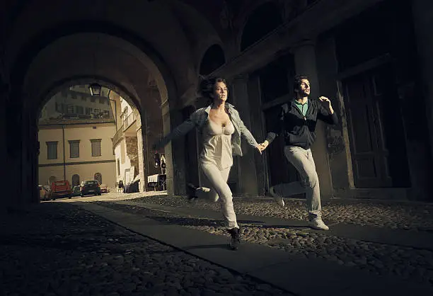 couple running thru an ominous street tunnel in small town of northern italy as someone bad was chasing them.