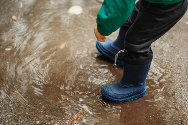 istock Boy feet in rubber boots while playing outside on a rainy day 1439215130