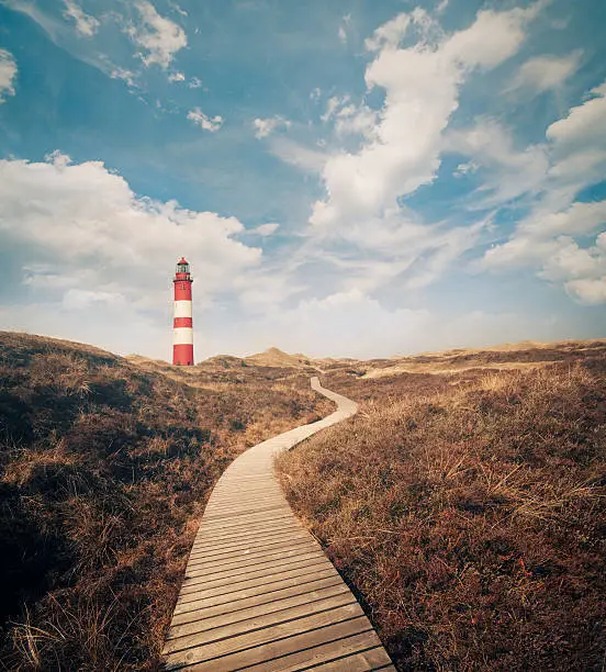 Lighthouse in the dunes with a wooden way