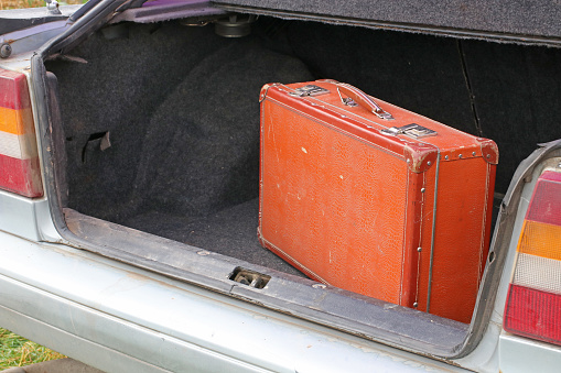 An old suitcase in the trunk of an old car. Travel concept.