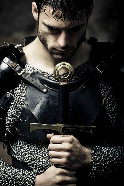 lonely knight in the darkness Mystical portrait of meditative Knight with sword,selective focus, very creative color retouching and hard lighting to underline the ancient medieval time,vignetting and possible noise,low key knight person stock pictures, royalty-free photos & images