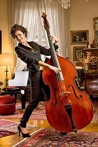 A wonderful,lively girl practices an old bass in her elegant living room.