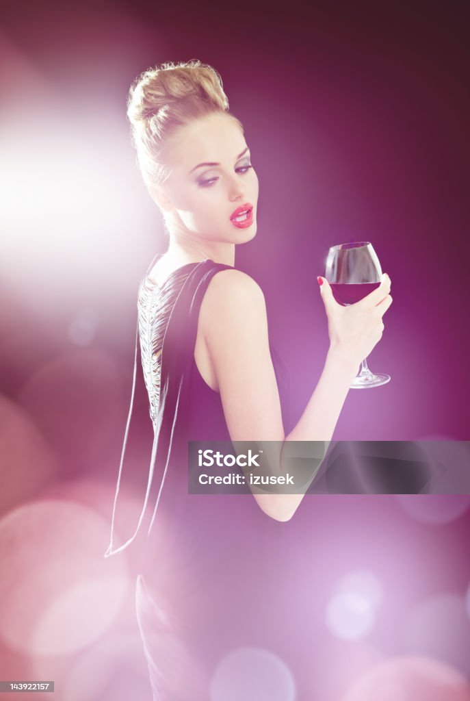 Beautiful woman in spotlights Glamour portrait of beautiful young woman wearing evening gown holding glass of wine, surrounded by spotlights.  Spot Lit Stock Photo
