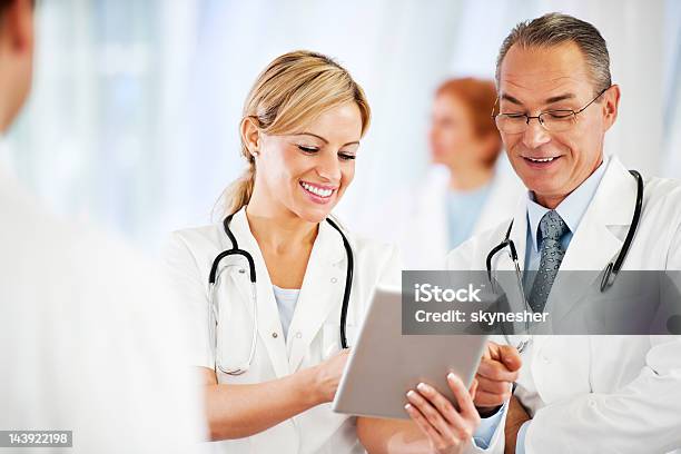 Successful Doctors Using Together A Touchpad Stock Photo - Download Image Now - Adult, Assistance, Built Structure