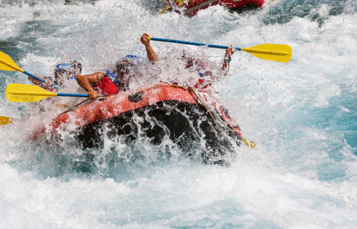 A group of people rafting on white water for sport and exhilaration.