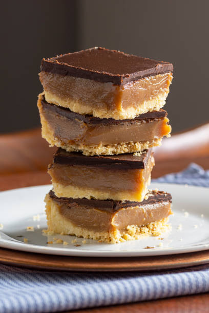 schottisches karamellstück oder millionärs-shortbread-süßwarendessert mit schichten schokolade und karamell über shortbread-kruste - shortbread caramel chocolate candy biscuit stock-fotos und bilder