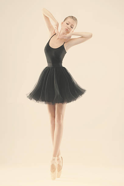 Full length studio portrait of a woman performing a contemporary dance jump while wearing black bodysuit.