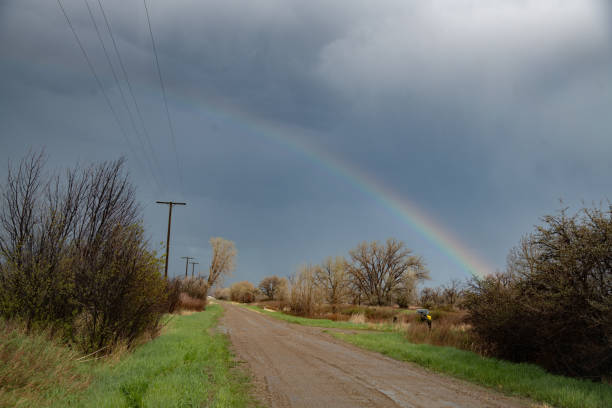 Afternoon thunderstorms and rainbow over Montana ranch muddy dirt road near Roundup and Billings Montana in northern USA, North America.
