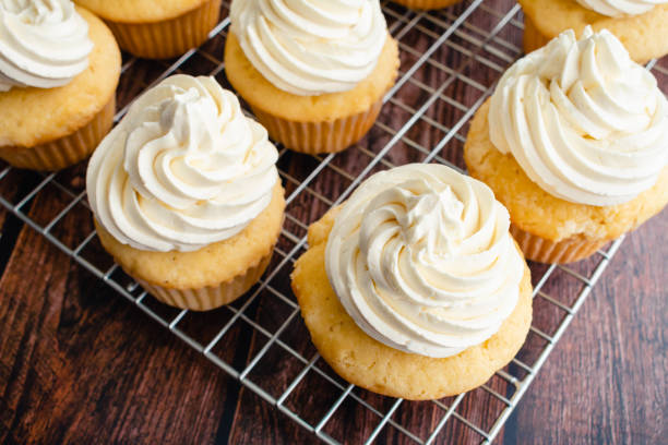 cupcakes à la vanille faits maison sur des grilles de cuisson - crème au beurre photos et images de collection