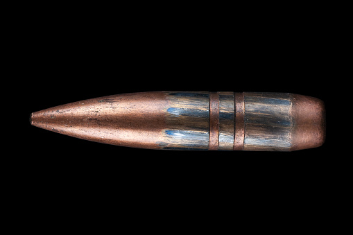 The 12.7mm bullet firing from a 12.7 mm heavy machine gun DShK or anti-materiel sniper rifle used by the former Soviet Union isolated on black background