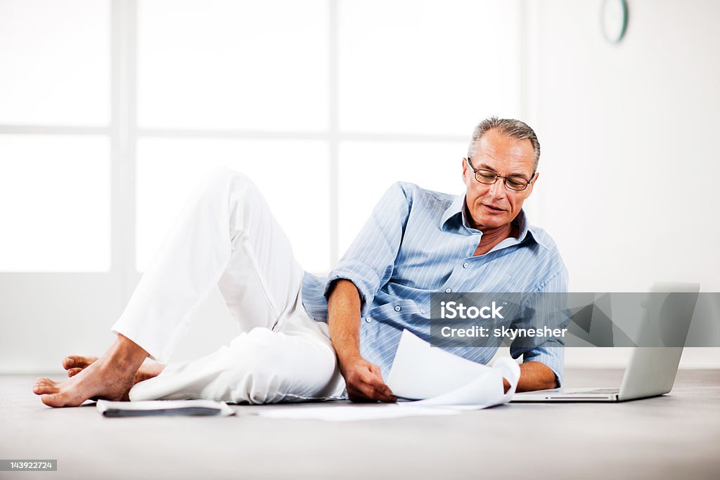 Mature homme Allongé sur le sol et à la recherche de documents - Photo de Homme d'affaires libre de droits