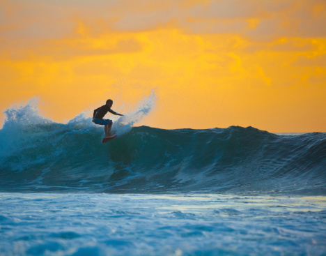surfer riding off perfect wave on sunset, Bali, Indonesia