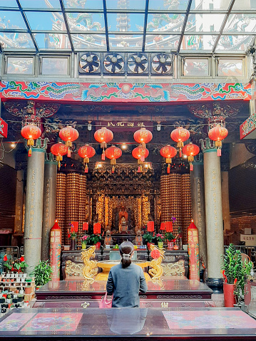 a Asian woman is praying in a old temple.  Traditional custom of chinese new year.