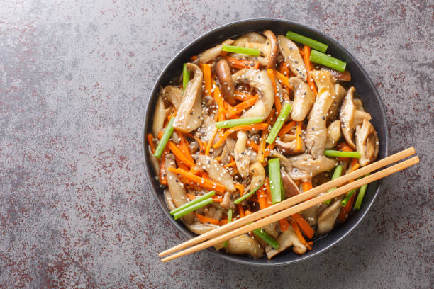 deliziosi funghi ostrica fritti e funghi shiitake con verdure in salsa piccante primo piano in un piatto. vista orizzontale dall'alto - funghi ostrica foto e immagini stock