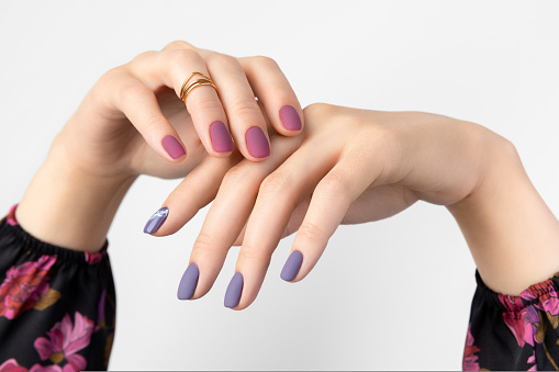 Beautiful womans hands with purple burgundy matte manicure. Fashionable spring summer nail design.