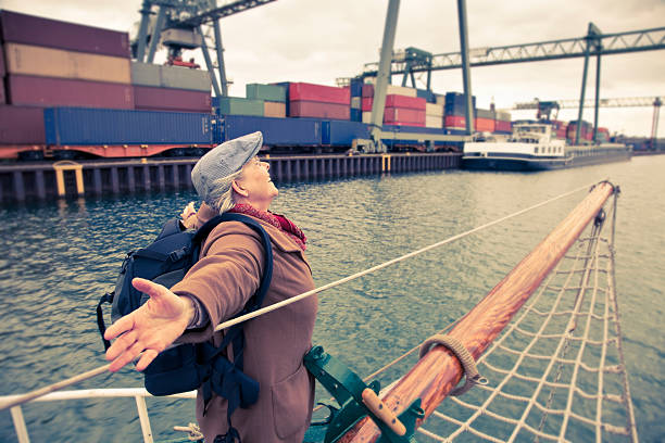 senior woman enjoying boat trip in Dortmunf harbour, standing at the front of the ship with outstretched arms