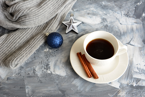 cup of coffee with cinnamon sticks and christmas spheres, close-up