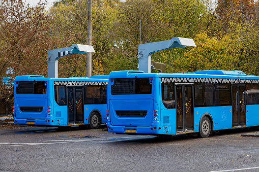 Electric buses of blue color are at the charging station.